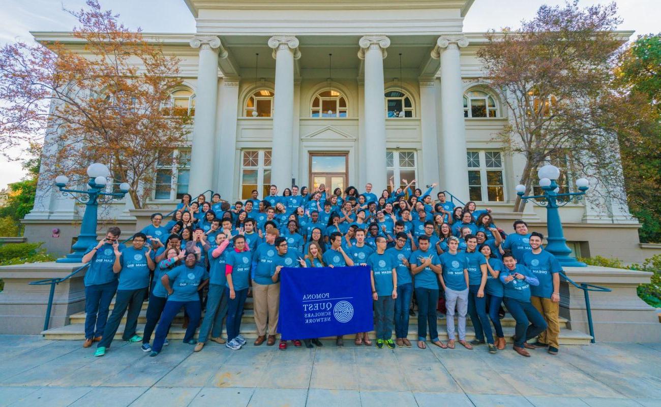 About 60 students with QuestBridge T-shirts making goofy gestures, standing in front of Carnegie Hall with Quest Scholars banner